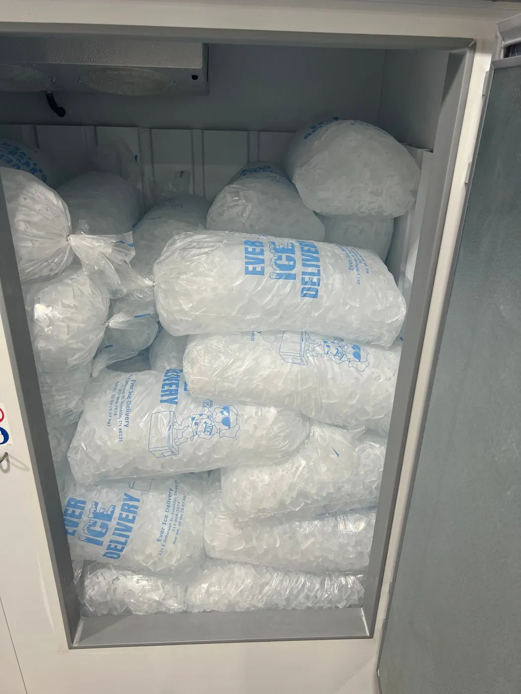 A freezer stacked with Ever Ice Delivery bags of ice